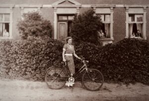 Eine Frau mit ihren Fahrrad vor einem Haus. In den 50er Jahren.
